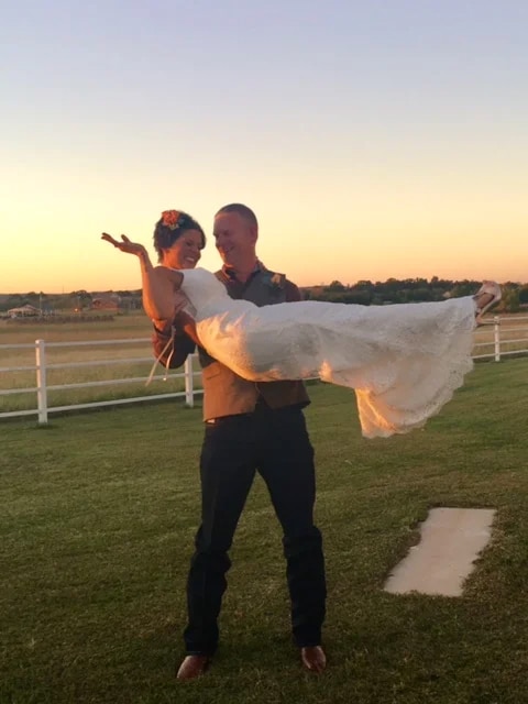 bride in wedding dress carried in her husband's arms