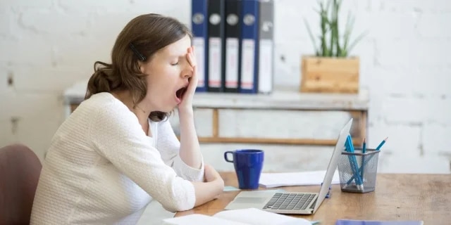 woman yawning at her desk